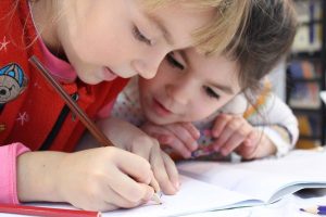 two kids writing in a book - darren yaw released news updates